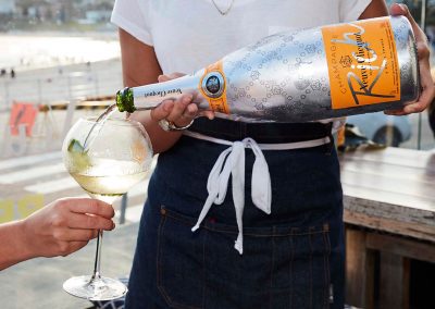 Close up waiter pouring champagne in glass Clicquot Beach Hut at Bondi Beach event