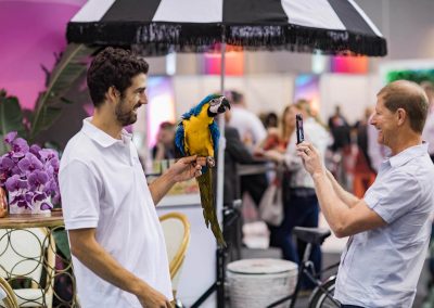 Man holding parrot guest taking picture Dual Australia Exhibition Stand - Miami Poolside