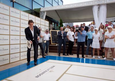 Roger holding racket at mini tennis court Game, Set & Moet with Roger Federer